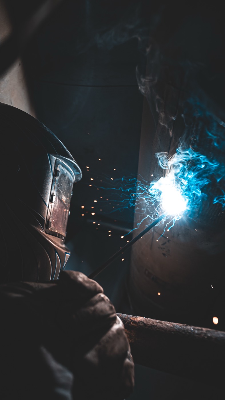 Welder in PPE with a cascade of sparks